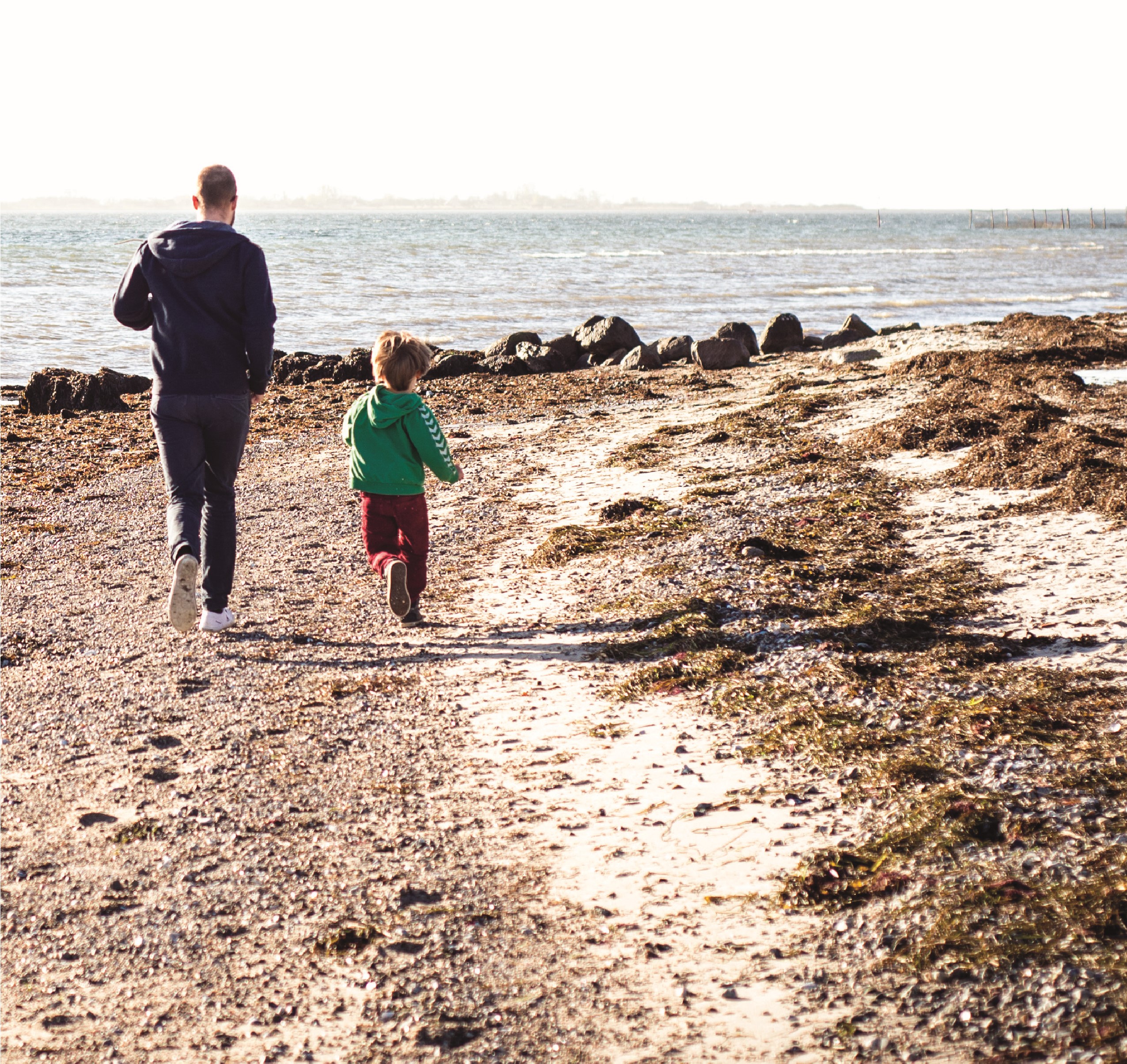 Far og barn løber på stranden